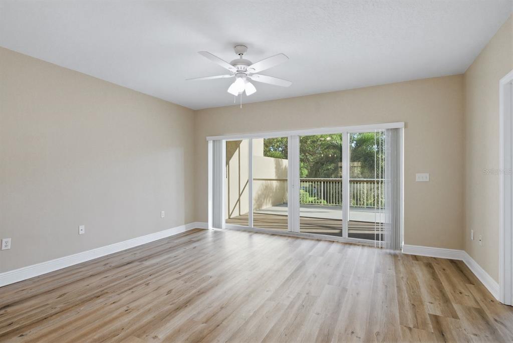 An empty room with light wood-look flooring, a ceiling fan, and sliding glass doors to a balcony — 960 STARKEY ROAD UNIT 5105, LARGO, FL