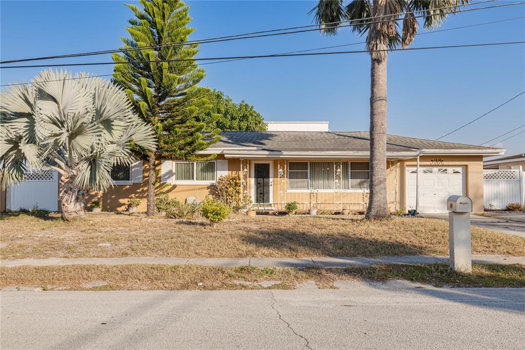 A single-story house with a tan exterior, a palm tree, and a front lawn — 1715 S JEFFERSON AVENUE, LARGO, FL