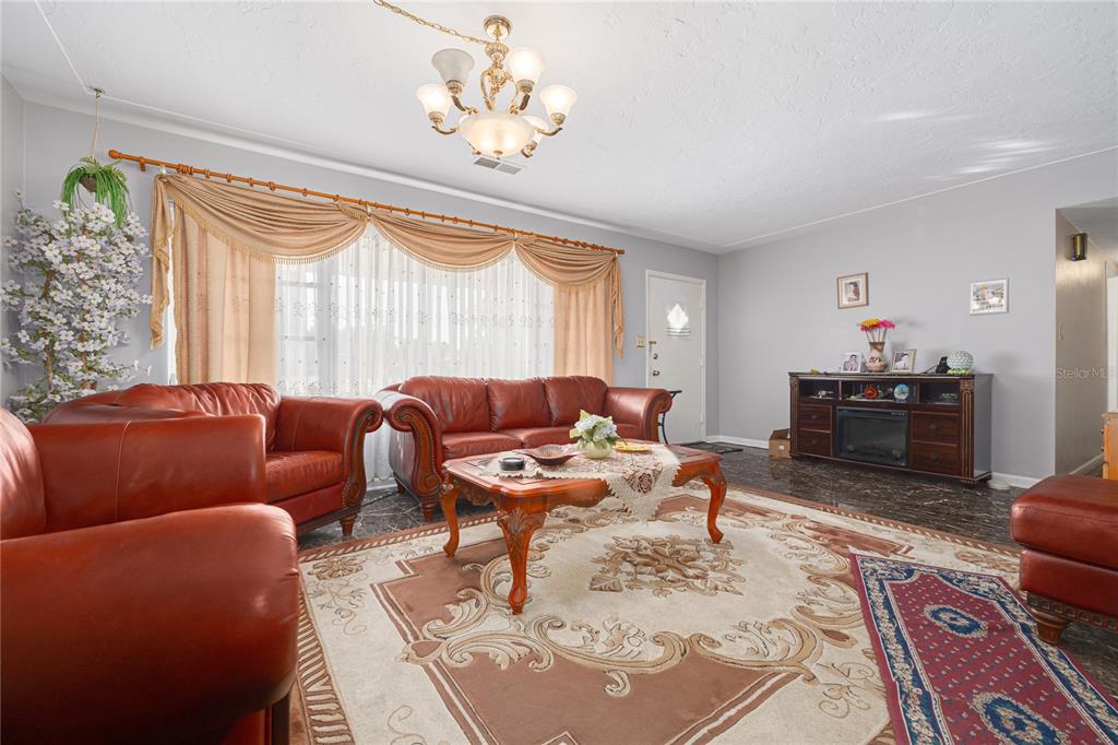 A living room features leather sofas, a coffee table, a patterned rug, and a chandelier — 1715 S JEFFERSON AVENUE, LARGO, FL