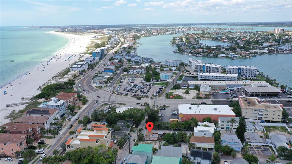 An aerial view shows a coastal town with a beach, waterway, and a red location marker — 101 95TH AVENUE, TREASURE ISLAND, FL
