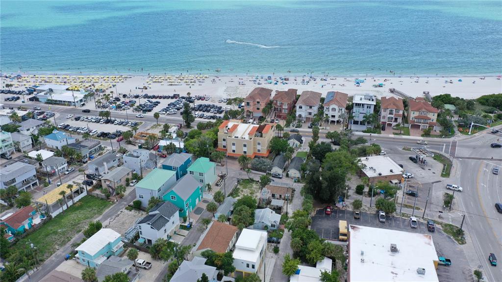 An aerial view shows a coastal neighborhood with houses, a parking lot, and a sandy beach — 101 95TH AVENUE, TREASURE ISLAND, FL