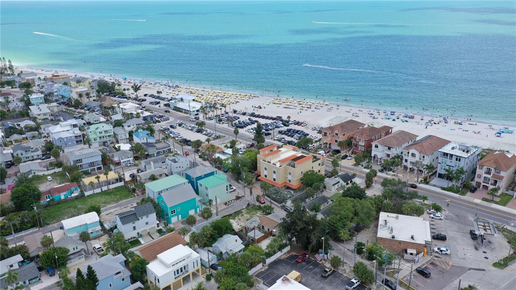 An aerial view shows a coastal neighborhood with houses, a parking lot, and a sandy beach — 101 95TH AVENUE, TREASURE ISLAND, FL