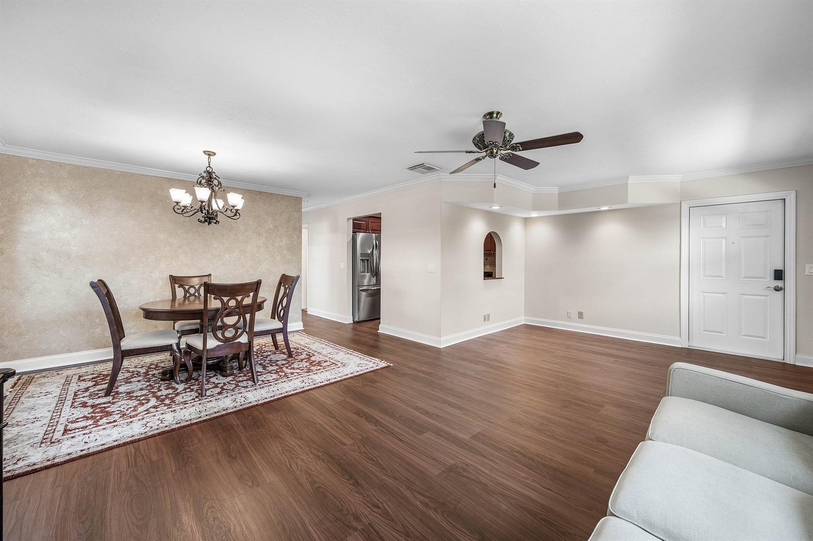 A dining area with a chandelier and rug sits adjacent to a living room space — 2303 Lowson Boulevard # D, Delray Beach FL 33445, DELRAY BEACH, FL