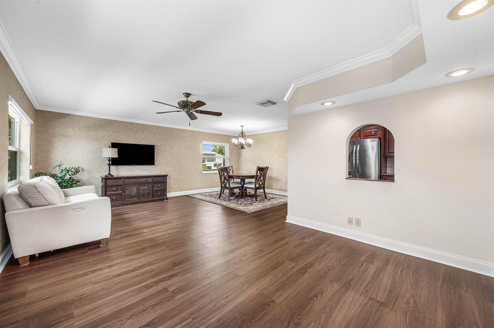 An open-concept living and dining area features wood-look flooring, neutral walls, and a kitchen pass-through — 2303 Lowson Boulevard # D, Delray Beach FL 33445, DELRAY BEACH, FL