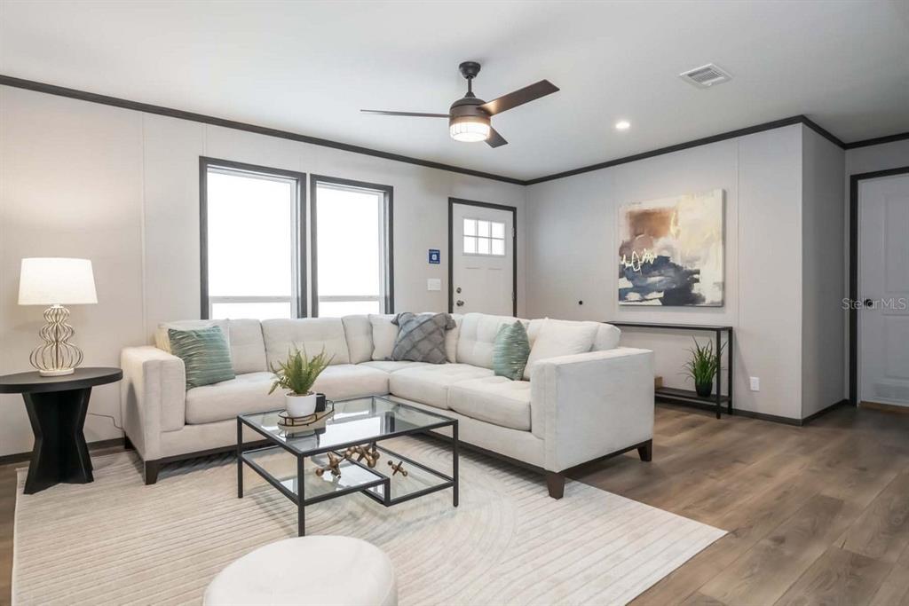A living room features a white sectional sofa, a glass coffee table, and wood-look flooring — 19520 NW 260TH STREET, OKEECHOBEE, FL