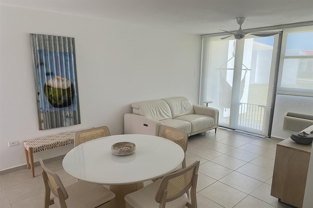 A bright living and dining area features a white sofa, round table, and wall art — C-116 MARBELA CASA DE PLAYA UNIT 1, ISABELA, PR