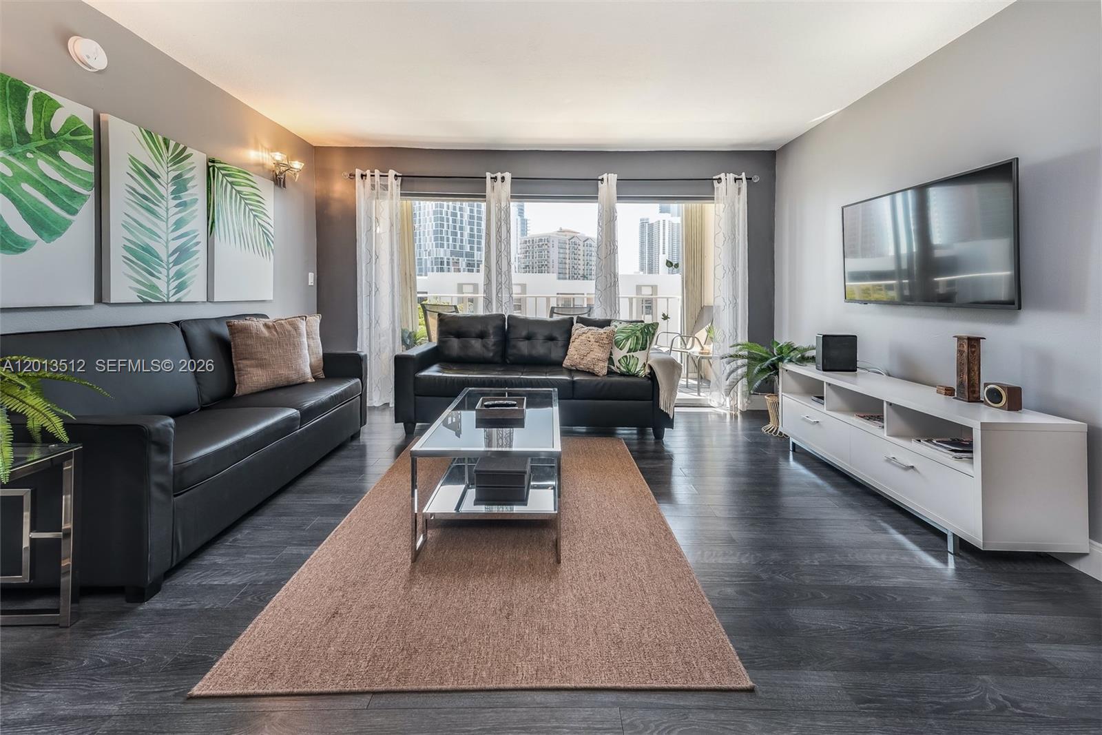 A living room features two black leather sofas, a glass coffee table, and dark flooring — 200 178th Dr # 604, Sunny Isles Beach FL 33160, SUNNY ISLES BEACH, FL