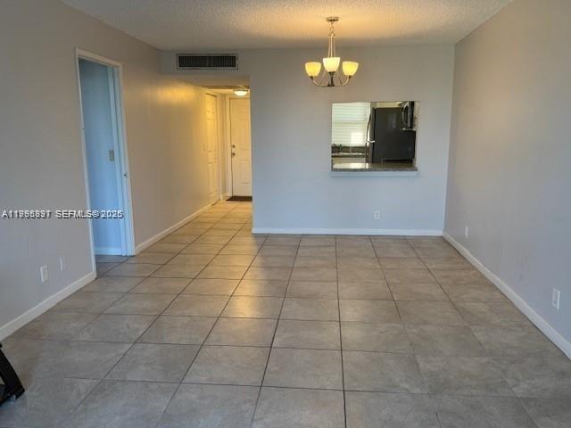 A living area with light-colored tile flooring, a chandelier, and a kitchen pass-through window — 9421 Evergreen Pl # 403, Davie FL 33324, DAVIE, FL