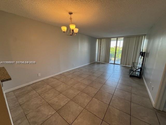An empty room features light-colored walls, a chandelier, and large square floor tiles — 9421 Evergreen Pl # 403, Davie FL 33324, DAVIE, FL