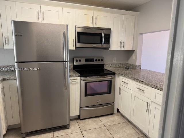 A kitchen features white cabinets, stainless steel appliances, and speckled granite countertops — 9421 Evergreen Pl # 403, Davie FL 33324, DAVIE, FL