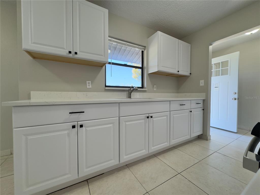 A kitchen features white cabinets, a white countertop, and a window above the sink — 1219 BROWNING AVENUE, ORLANDO, FL