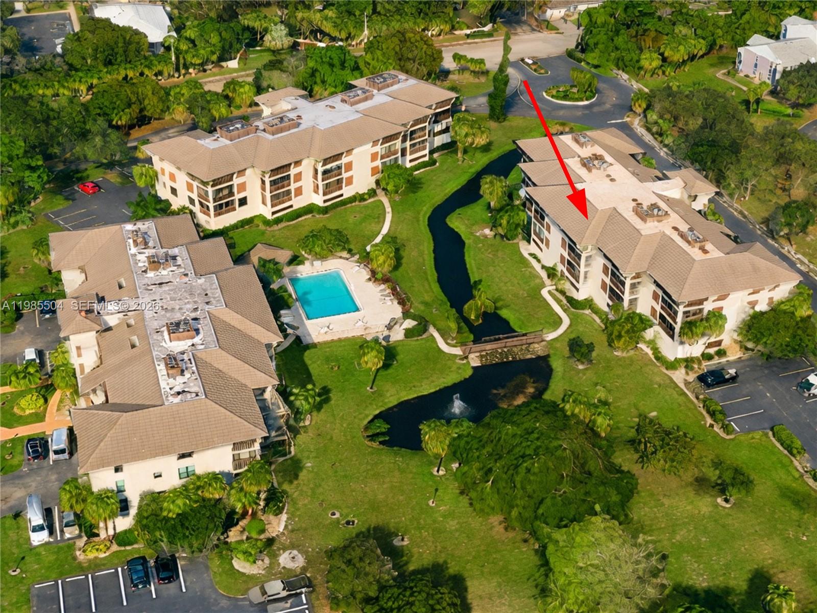 An aerial view shows three multi-story apartment buildings surrounding a swimming pool and pond — 166 SE St Lucie Blvd # Un # 203, Stuart FL 34996, STUART, FL