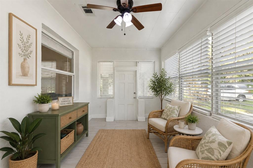 A sunroom features white walls, tile flooring, a ceiling fan, and wicker chairs by windows — 2013 E HENRY AVENUE, TAMPA, FL