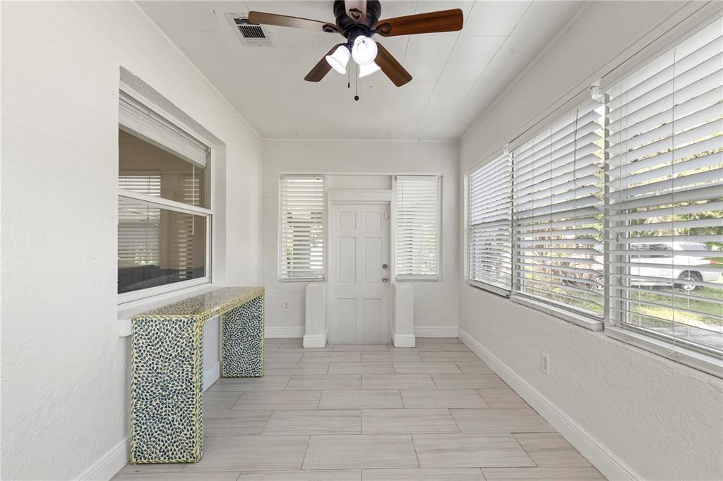 A sunroom with white walls, light tile flooring, a ceiling fan, and large windows — 2013 E HENRY AVENUE, TAMPA, FL