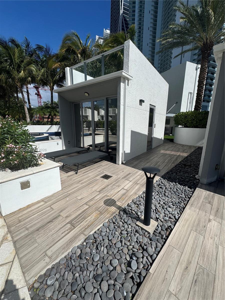 A small white structure with glass doors sits on a wood-look patio with stone landscaping — 851 NE 1st ave # 7, Miami FL 33132, MIAMI, FL