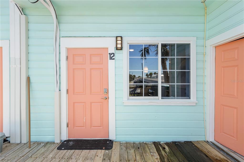 A light blue exterior wall features a peach-colored door labeled 12 and a window — 491 DOCK STREET, CEDAR KEY, FL