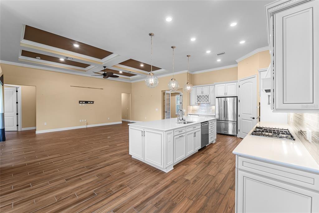 A kitchen with a large white island and stainless steel appliances opens to a living area — 5700 SWEET LEAF WAY, SARASOTA, FL