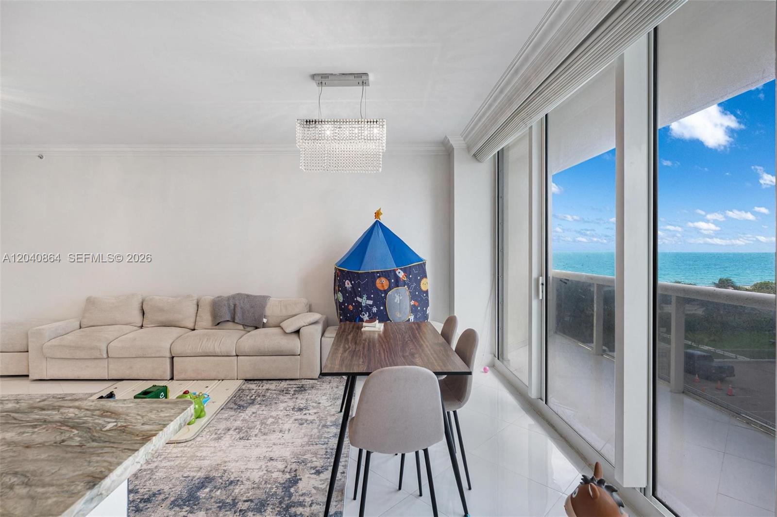 A living and dining area features a beige sofa, a dining table, and ocean views — 9559 Collins Ave # J, Surfside FL 33154, SURFSIDE, FL