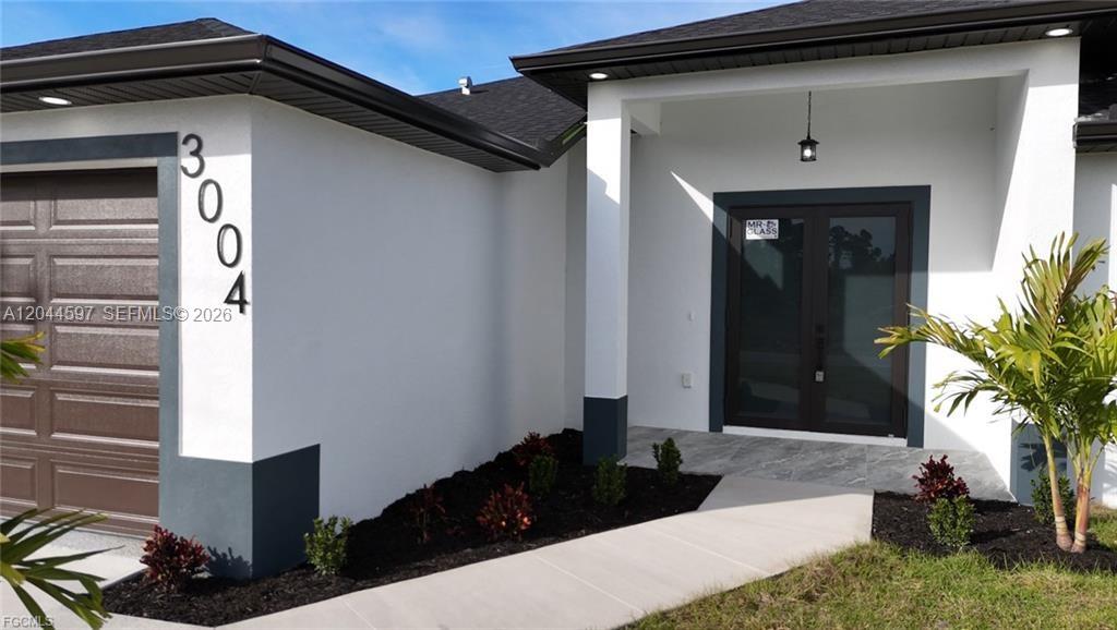 The exterior of a modern house features a garage, a covered entryway, and landscaping — 3004 SW 4TH ST, Lehigh Acres FL 33976, LEHIGH ACRES, FL