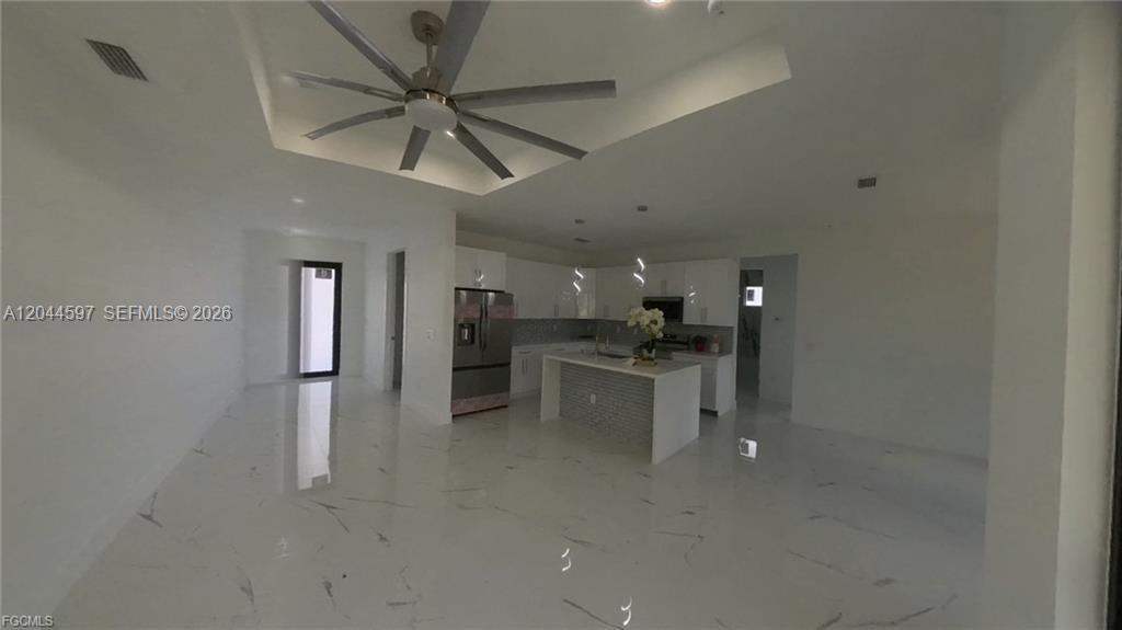 A modern open-concept kitchen and living area features white cabinetry, a central island, and tile flooring — 3004 SW 4TH ST, Lehigh Acres FL 33976, LEHIGH ACRES, FL