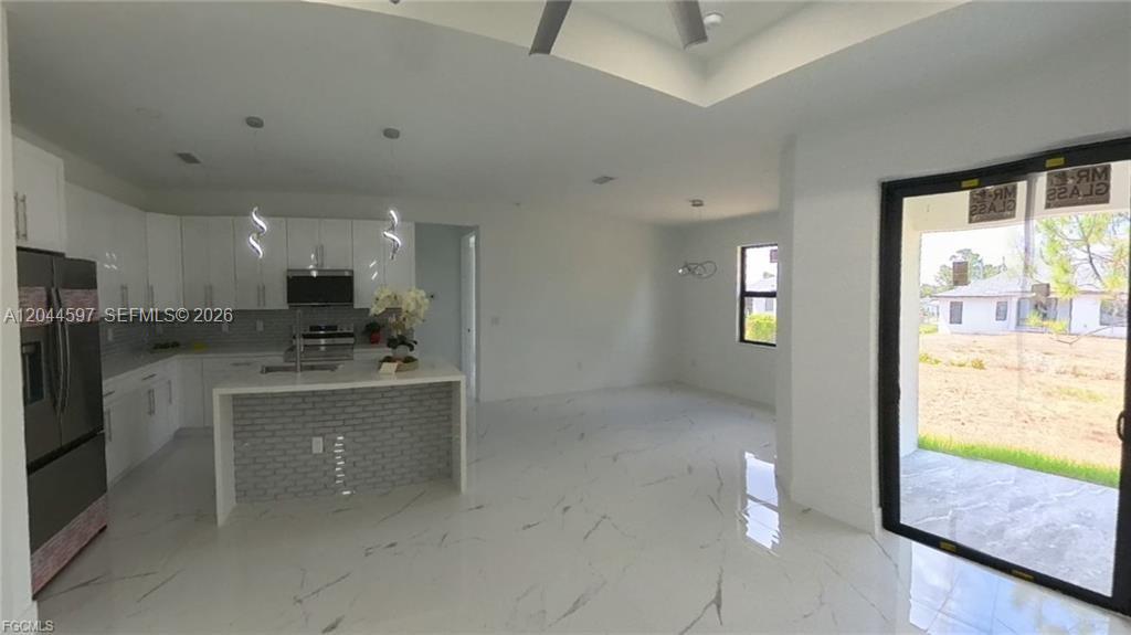 A modern kitchen features white cabinetry, a gray brick island, and large white floor tiles — 3004 SW 4TH ST, Lehigh Acres FL 33976, LEHIGH ACRES, FL
