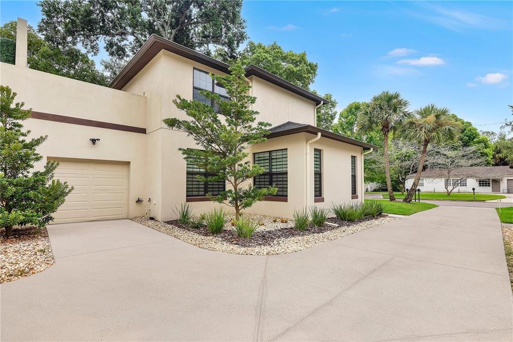 A two-story stucco house with a garage and a concrete driveway surrounded by landscaping — 2251 NAIRN DRIVE, WINTER PARK, FL