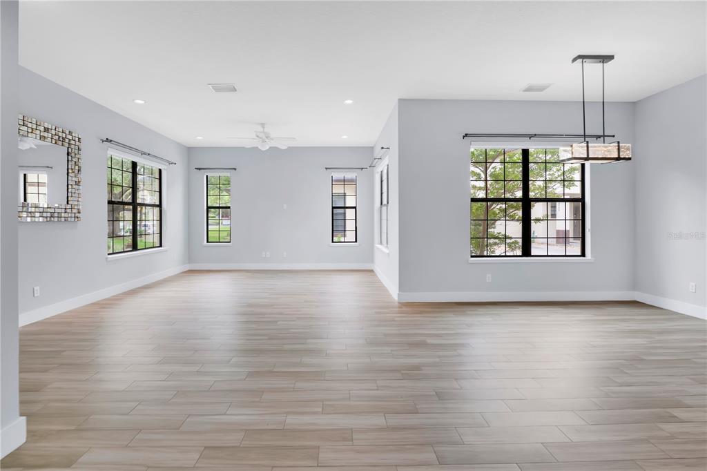 An empty, light-filled living area features gray walls, wood-look tile flooring, and a modern chandelier — 2251 NAIRN DRIVE, WINTER PARK, FL