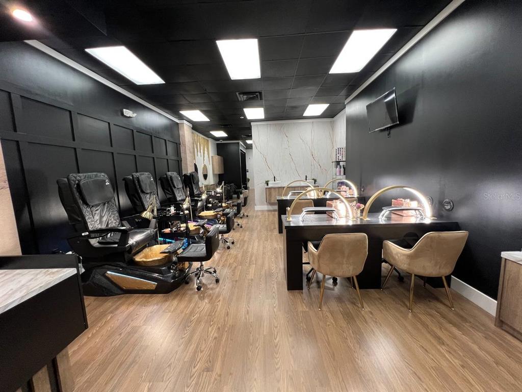 A modern nail salon features pedicure chairs, manicure stations, black walls, and wood-look flooring — 14650 GATORLAND DRIVE UNIT 8, ORLANDO, FL