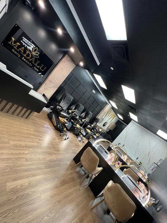 A modern nail salon features black walls, wood-look flooring, pedicure chairs, and manicure stations — 14650 GATORLAND DRIVE UNIT 8, ORLANDO, FL