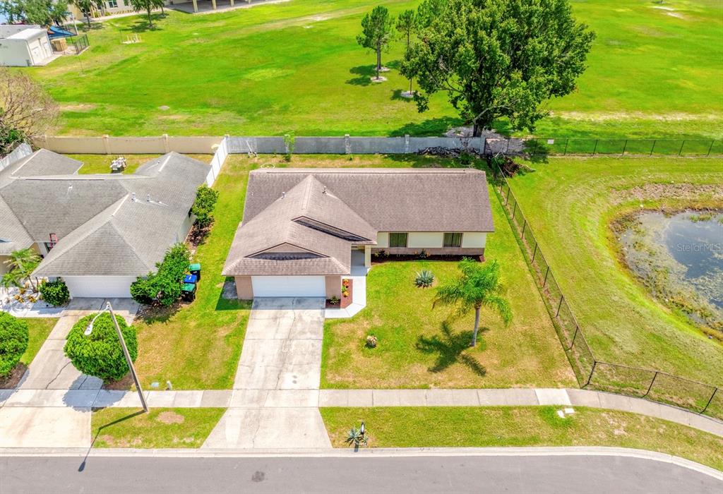 An aerial view shows a single-story house with a driveway, lawn, and adjacent pond — 2790 MUSCATELLO STREET, ORLANDO, FL