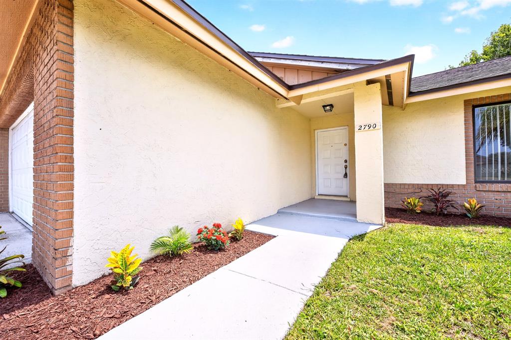 The exterior of a house features a white front door, brick accents, and a walkway — 2790 MUSCATELLO STREET, ORLANDO, FL
