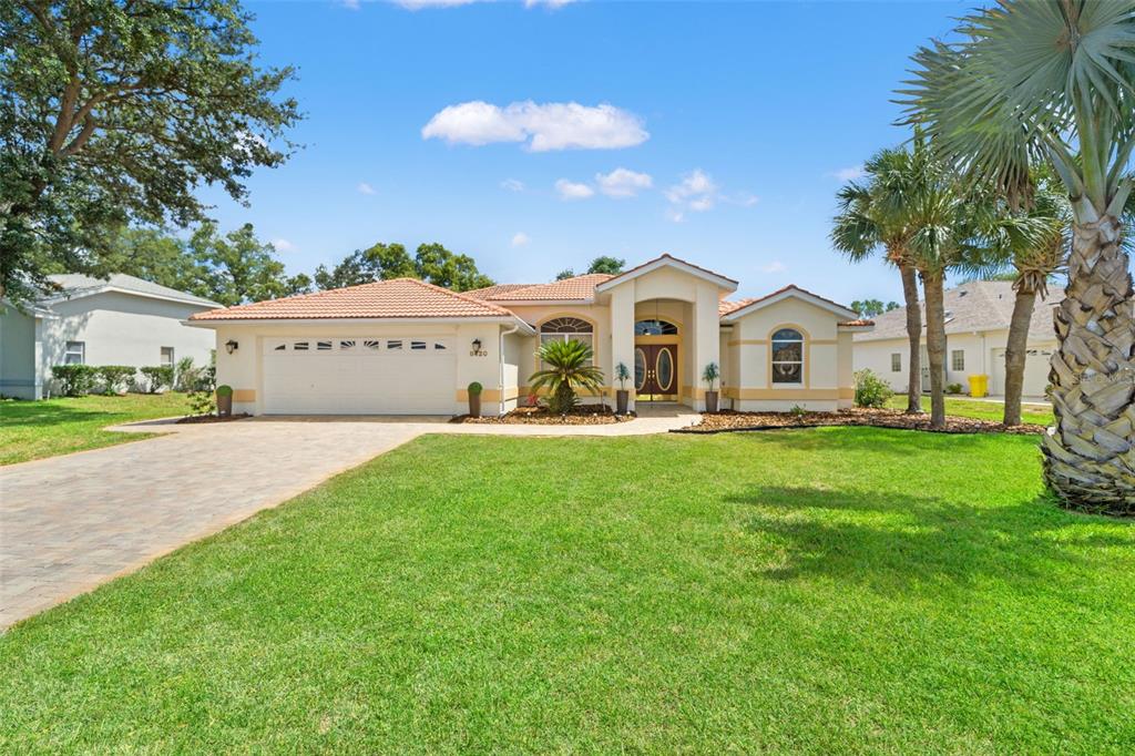 A single-story house with a tile roof, two-car garage, and palm trees in the front yard — 8420 MAYBELLE DRIVE, WEEKI WACHEE, FL
