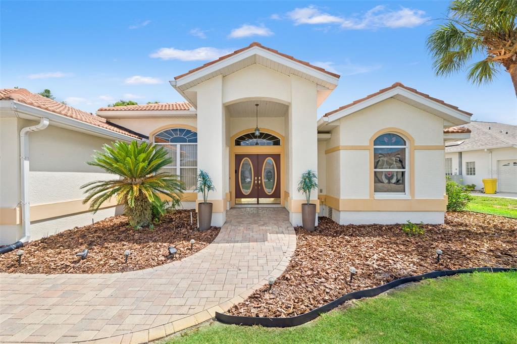 A single-story house with a paved walkway leading to a double-door entrance under a portico — 8420 MAYBELLE DRIVE, WEEKI WACHEE, FL