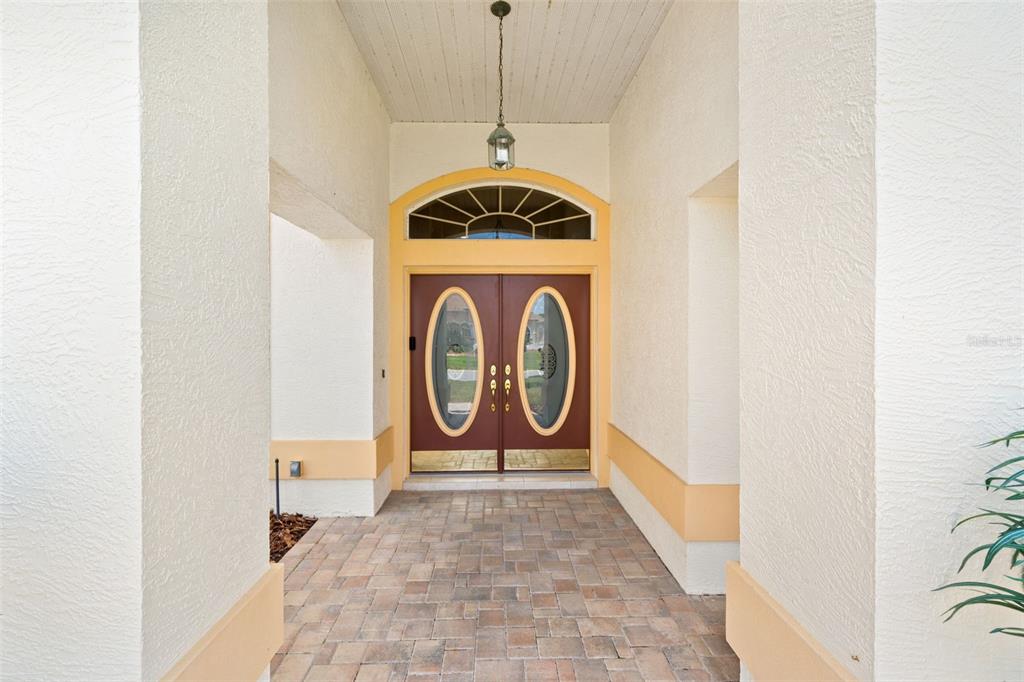 A covered entryway features a brick paver floor and double doors with oval glass inserts — 8420 MAYBELLE DRIVE, WEEKI WACHEE, FL