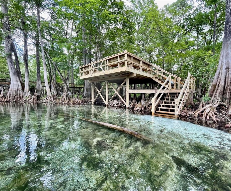 A wooden observation deck stands on stilts over a clear, shallow spring surrounded by trees — 1376 RIVERSIDE AVENUE, FORT WHITE, FL