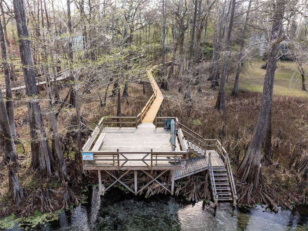 An elevated wooden deck and boardwalk extend over a swampy area with cypress trees — 1376 RIVERSIDE AVENUE, FORT WHITE, FL