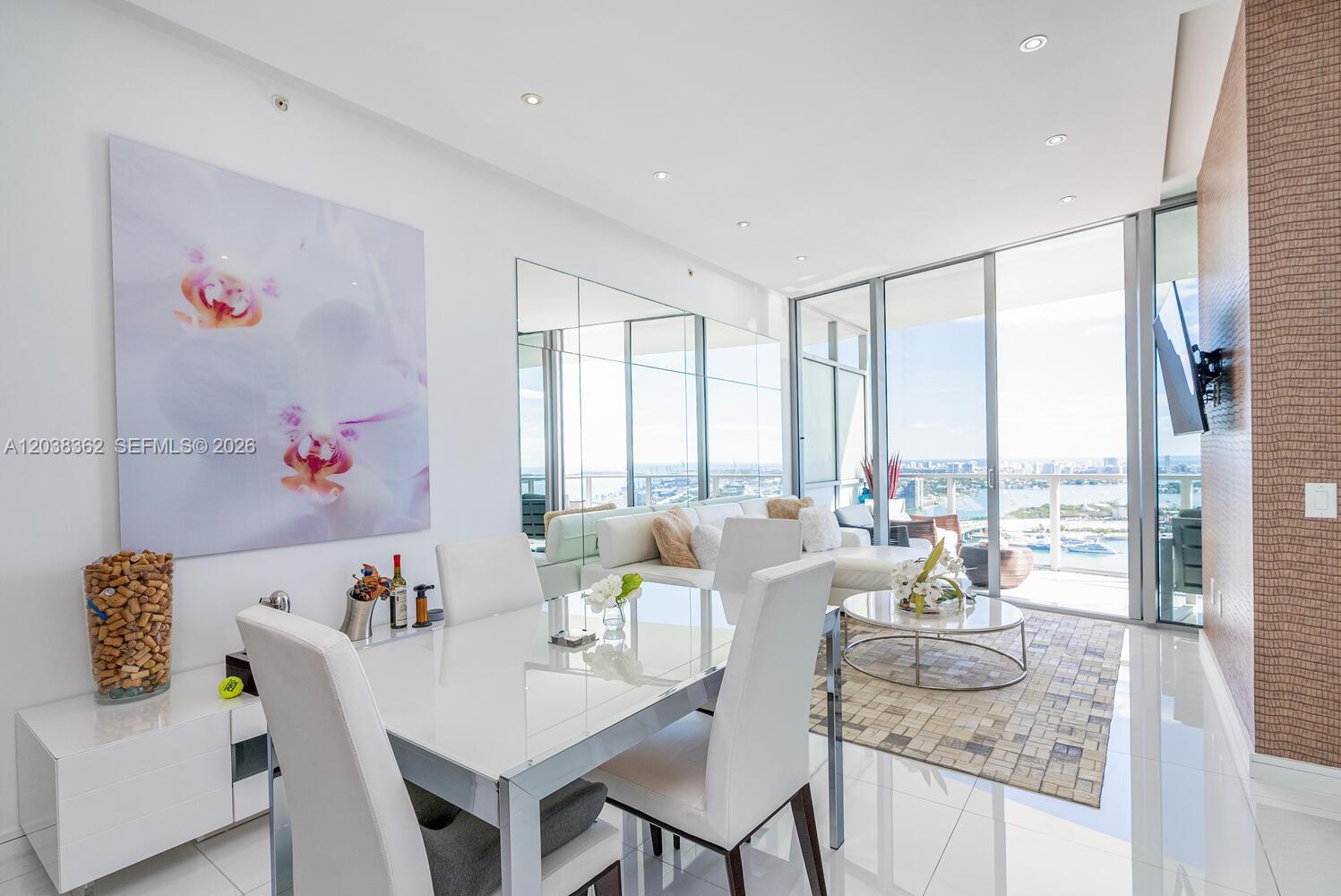 A modern dining and living area features white furniture, a large orchid print, and floor-to-ceiling windows — 1100 Biscayne Blvd # 4103, Miami FL 33132, MIAMI, FL