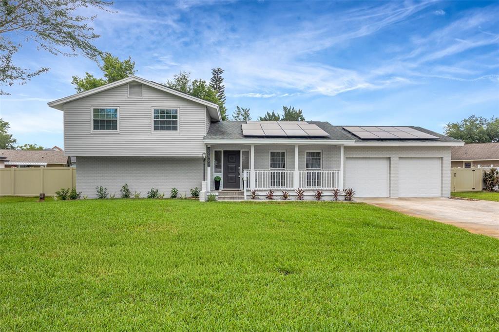 A two-story house with light gray siding, a brick lower level, and rooftop solar panels — 22369 SOUTHSHORE DRIVE, LAND O LAKES, FL