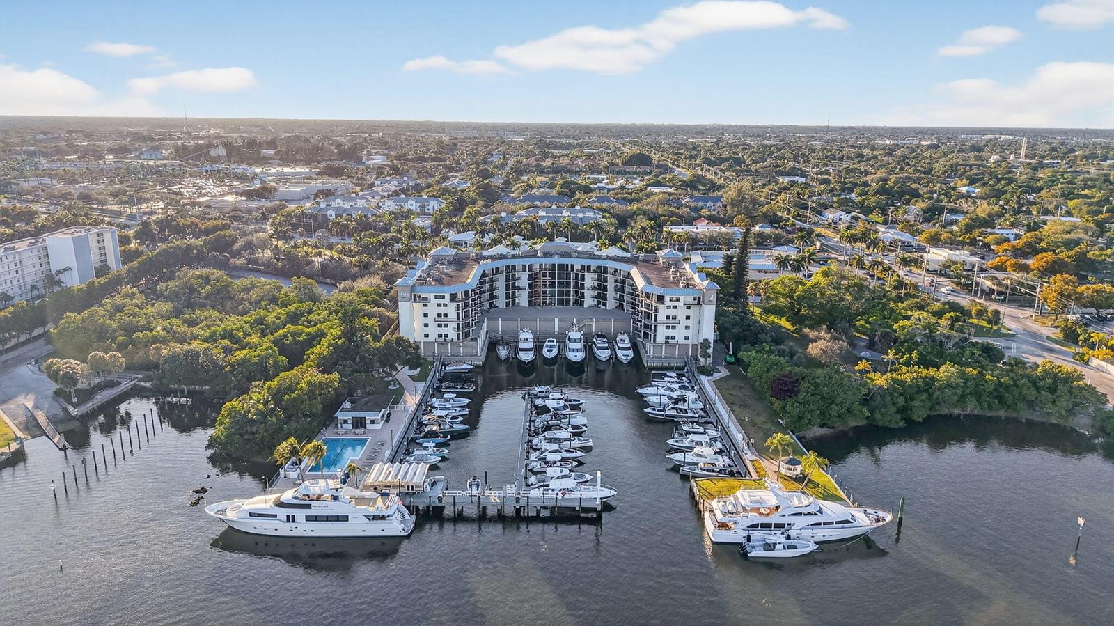 An aerial view shows a multi-story residential building with a private marina and swimming pool — 1035 S Federal Highway # 402, Delray Beach FL 33483, DELRAY BEACH, FL