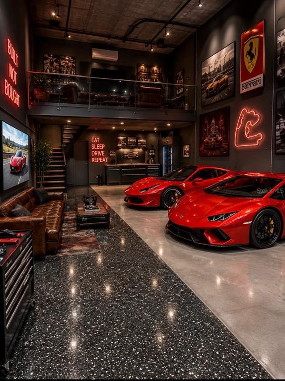 A luxury garage features two red sports cars, a lounge area, and a mezzanine level — 5431 COMMUNICATIONS PARKWAY UNIT 20, SARASOTA, FL