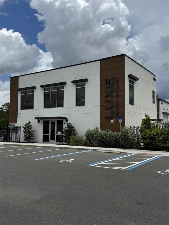 A modern two-story commercial building with white walls, wood-look accents, and a paved parking lot — 5431 COMMUNICATIONS PARKWAY UNIT 20, SARASOTA, FL