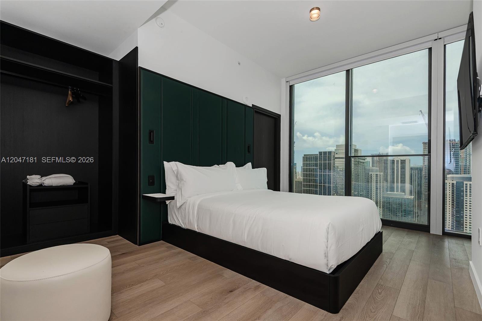 A modern bedroom features a dark green headboard, a platform bed, and floor-to-ceiling city views — 20 NE 11 # 4404, Miami FL 33132, MIAMI, FL