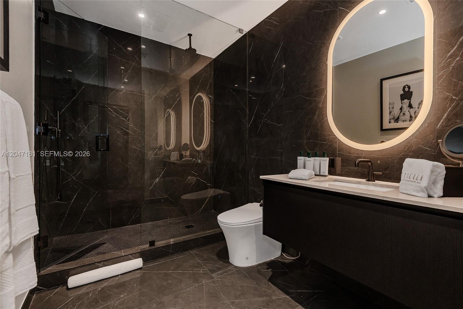 A modern bathroom features dark marble walls, a glass-enclosed shower, and a floating vanity — 20 NE 11 # 4404, Miami FL 33132, MIAMI, FL