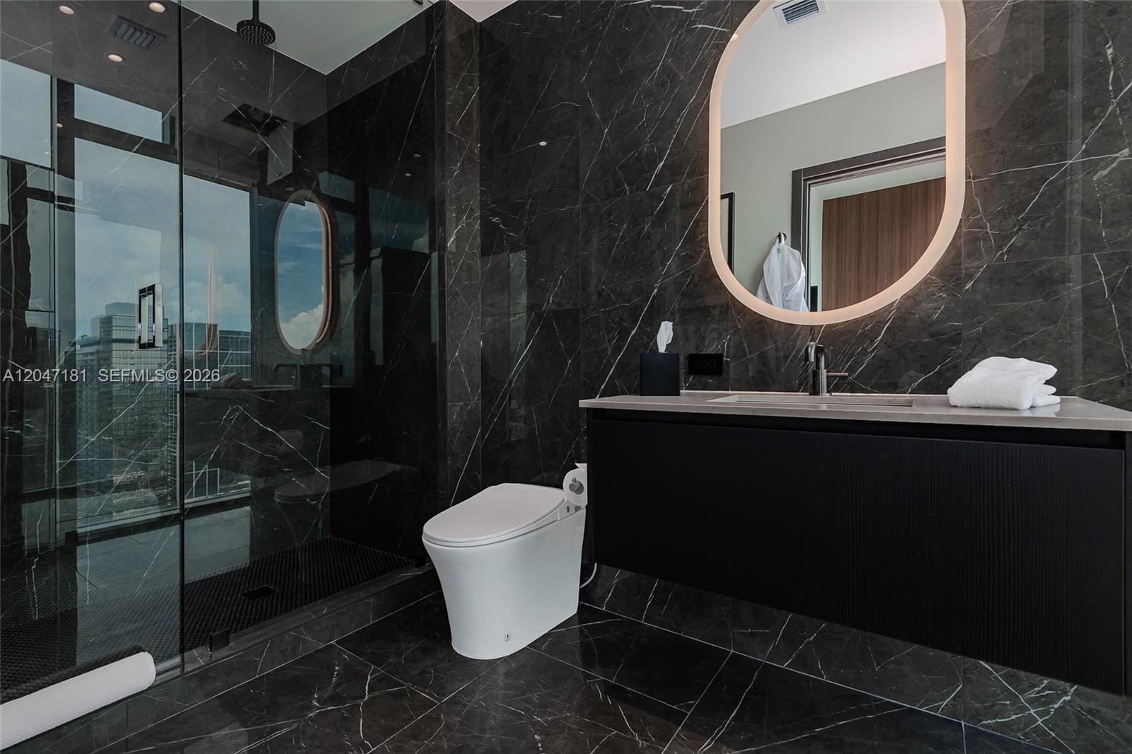 A modern bathroom features dark marble walls, a floating vanity, and a glass-enclosed shower — 20 NE 11 # 4404, Miami FL 33132, MIAMI, FL