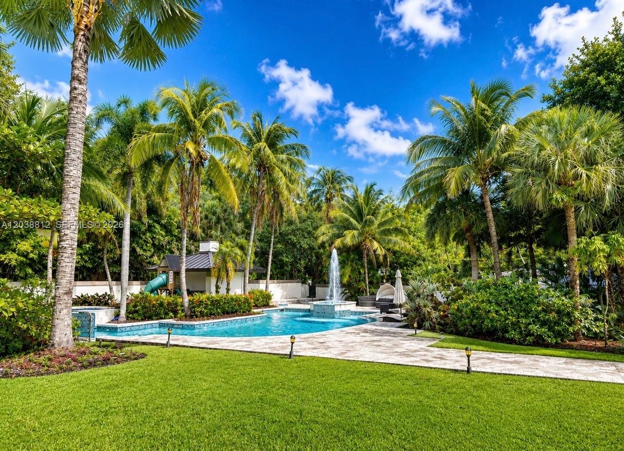 A swimming pool with a fountain is surrounded by palm trees and a stone patio — 10395 SW 67th Ave, Pinecrest FL 33156, PINECREST, FL