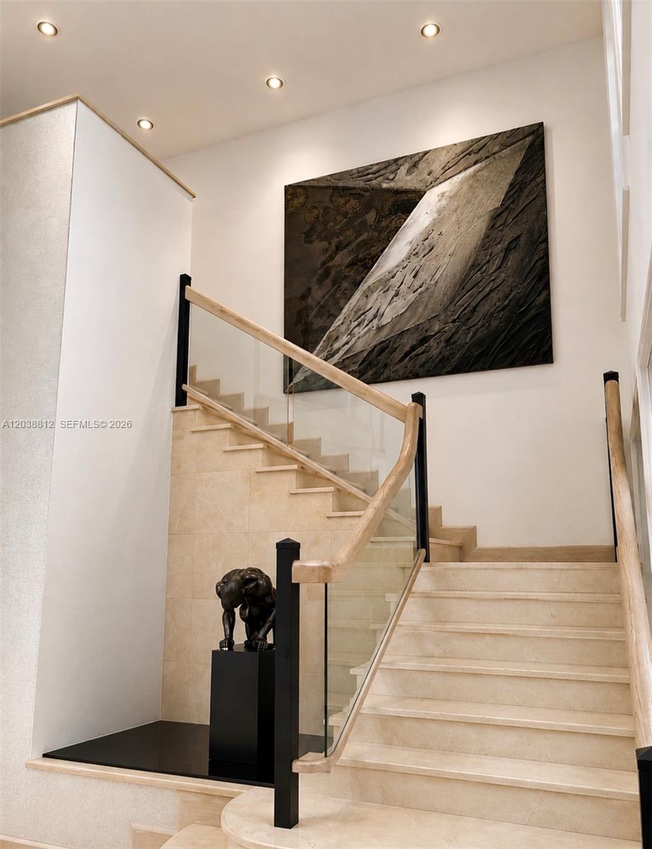 A staircase with stone steps, glass railings, and a wooden handrail features a large abstract painting — 10395 SW 67th Ave, Pinecrest FL 33156, PINECREST, FL