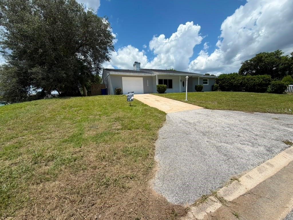 A single-story house with a gray exterior, a white garage door, and a concrete driveway — 1822 BANYAN TREE DRIVE, EDGEWATER, FL
