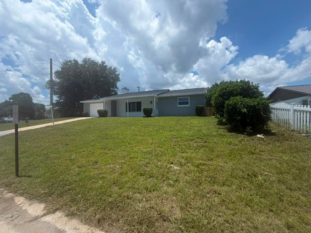A single-story house with a gray exterior, a white garage door, and a large front lawn — 1822 BANYAN TREE DRIVE, EDGEWATER, FL