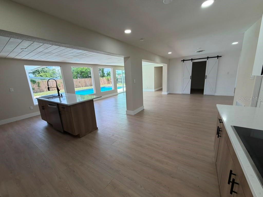 A kitchen island and open living area feature light wood flooring and a backyard pool — 1822 BANYAN TREE DRIVE, EDGEWATER, FL