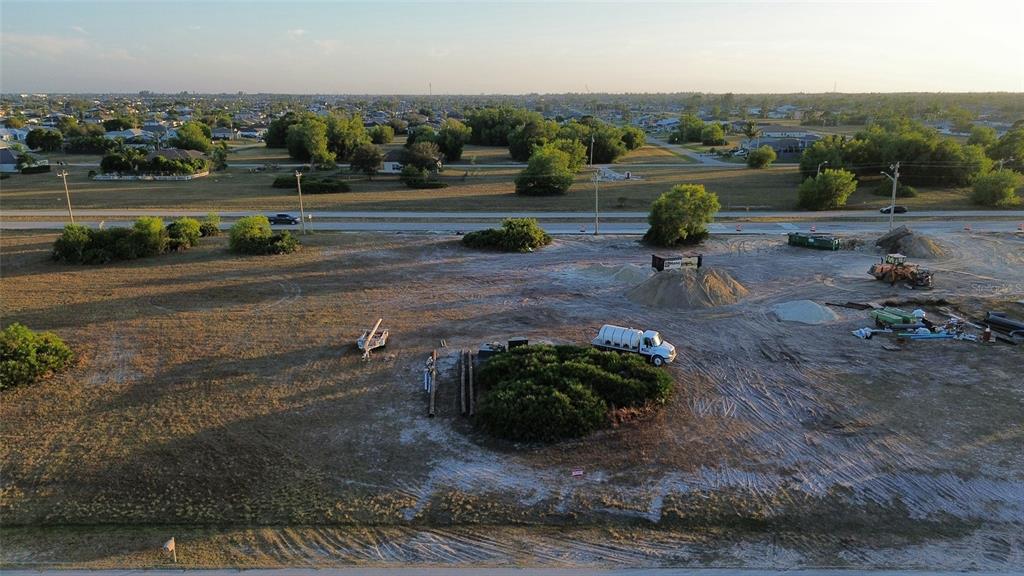 An aerial view shows a cleared, sandy construction lot with heavy equipment and scattered vegetation — 1508 NW 16TH TERRACE, CAPE CORAL, FL